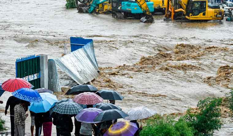 Nepali residents look at floodwaters after the Balkhu River overflowed following monsoon rains at the Kalanki area of Kathmandu | AFP