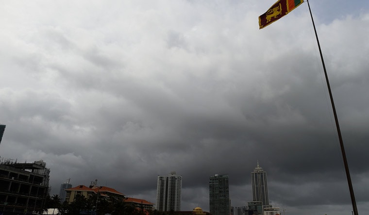 Sri Lanka's national flag flies in the rain along the Galle Face promenade as monsoon clouds loom in the background during monsoon winds in Colombo | AFP