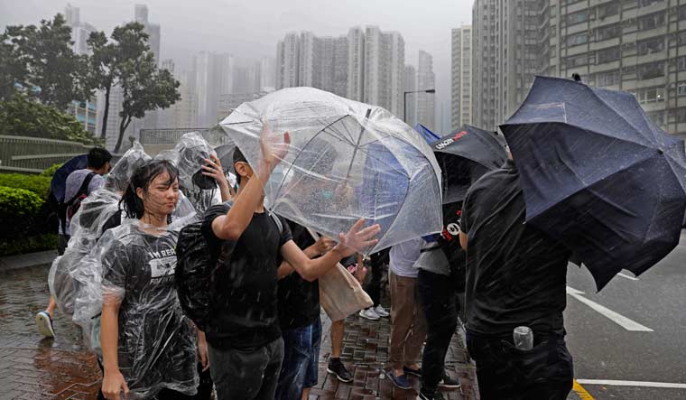 Protesters hold umbrellas against strong winds and heavy rain from tropical storm Wipha in Hong Kong | AP