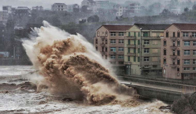 Waves hit a sea wall in front of buildings in Taizhou, China's eastern Zhejiang province on August 9, 2019 | AFP
