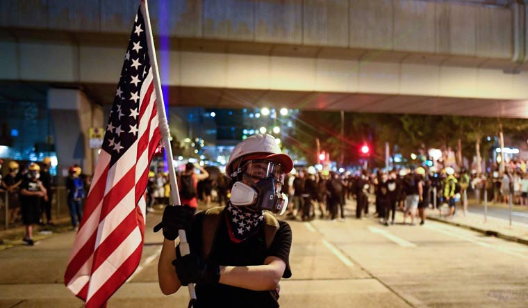 A pro-democracy protester waves a US national flag in Tsim Sha Tsui district | AFP
