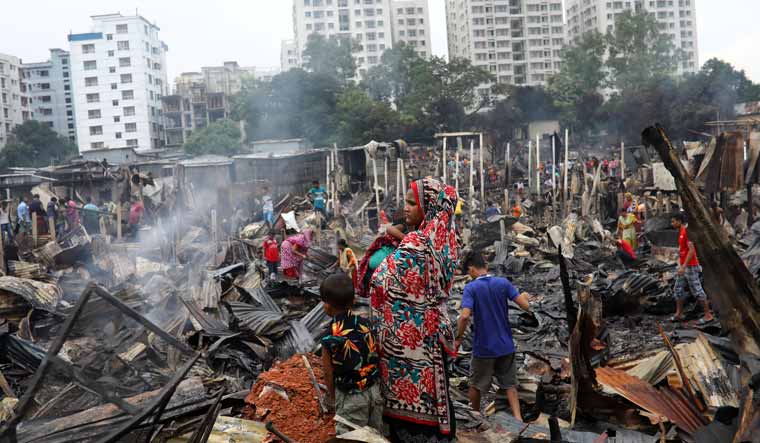 Slum dwellers gather near their shelters after a massive fire gutted their homes in Dhaka | Reuters