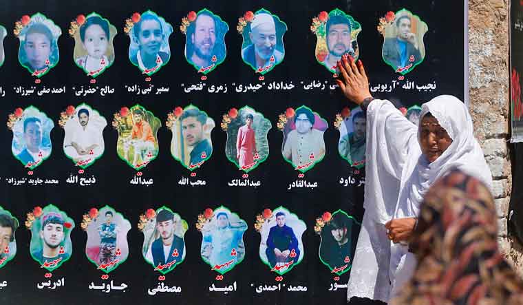 An Afghan woman cries as she touches a banner displaying photographs of victims of the Dubai City wedding hall bombing during a memorial service in Kabul, Afghanistan | AP