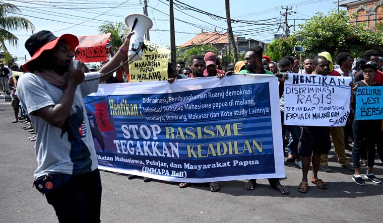People hold banners and placards against the recent surge in violent protests in Indonesia's eastern Papua province, at a rally in Denpasar on Indonesia's resort island of Bali | AFP