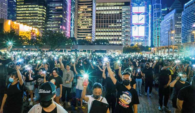 [File] Secondary school students raise their phone torches as they sing 'Do You Hear the People Sing' from 'Les Miserables' while attending a rally in Hong Kong | AFP