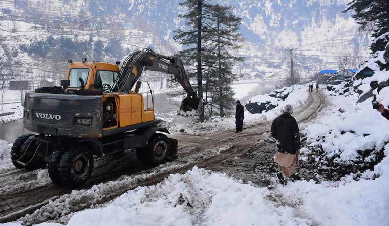 Workers with heavy machinery clear a snow-covered road in Keran, a small town in Neelum Valley, in PoK | AP