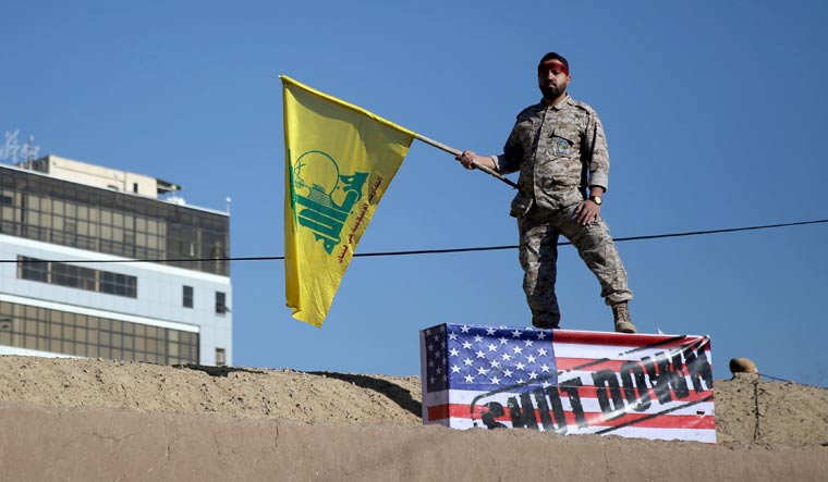 An Iranian guard holds a Hezbollah flag during a funeral procession and burial for Iranian Major-General Qassem Soleimani, head of the elite Quds Force, who was killed in an air strike at Baghdad airport, at his hometown in Kerman, Iran January 7, 2020 | Reuters