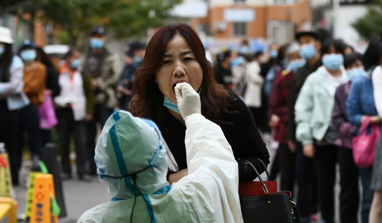 A medical worker in protective suit collects a swab from a woman for nucleic acid testing, following new cases of coronavirus disease (COVID-19) in Qingdao, Shandong province, China October 13, 2020. Picture taken October 13, 2020 | China Daily via REUTERS
