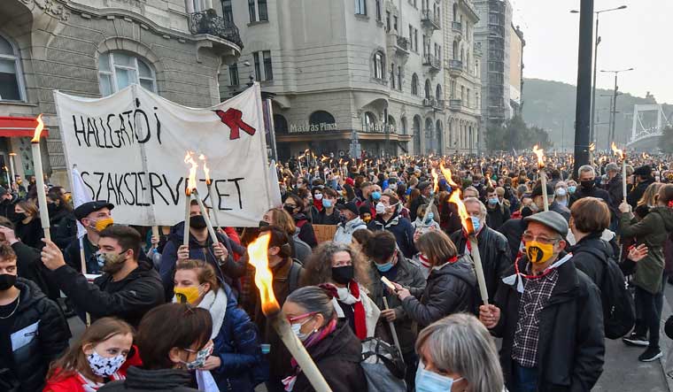 University students and their sympathizers protest holding torches and a banner reading 'Trade union of students' in Budapest | AFP