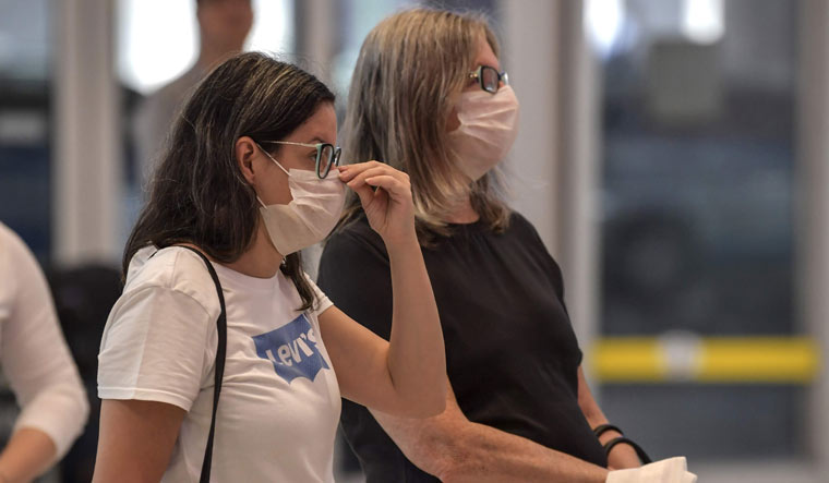 Passengers, wearing masks as a precautionary measure to avoid contracting the coronavirus, travel through Guarulhos International Airport, in Guarulhos, Sao Paulo, Brazil | AFP