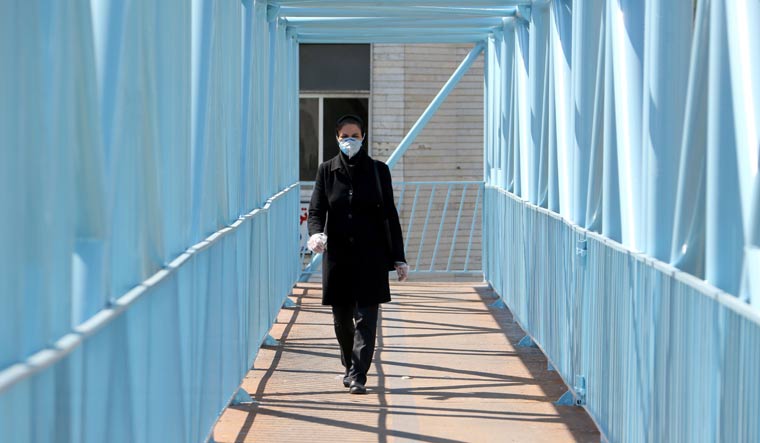 An Iranian pedestrian walks while wearing a protective mask in Tehran | AFP