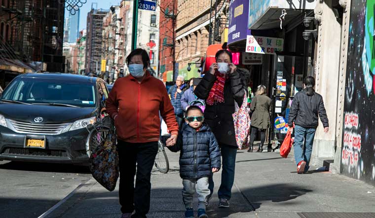 People wear face masks as they walk down the street in Chinatown in New York | AP