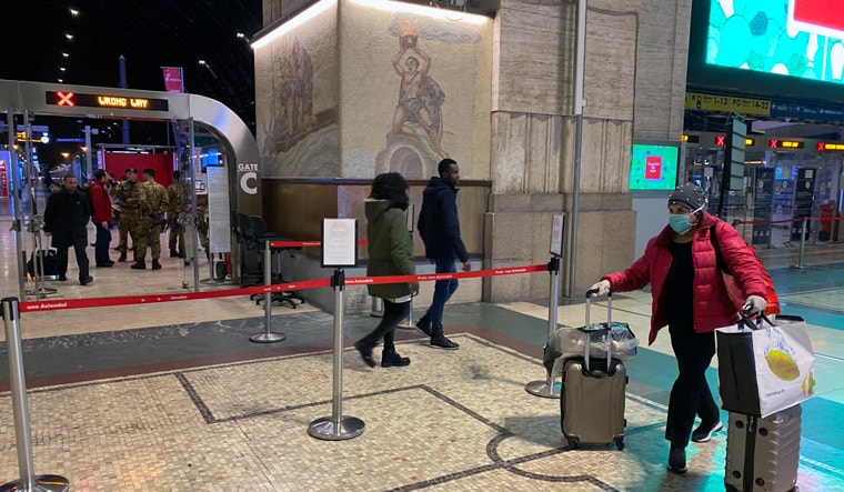 A woman wearing a protective face mask walks with her luggages inside Milan's main train station as Italian authorities prepare to lock down Lombardy to prevent the spread of the highly infectious coronavirus in Milan | Reuters