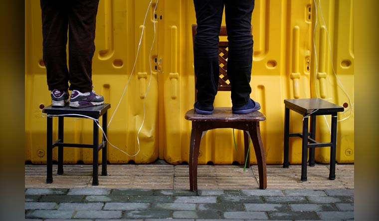 Residents pay for groceries by standing on chairs to peer over barriers set up to ring-fence a wet market on a street in Wuhan, Hubei province, the epicentre of China's coronavirus disease (COVID-19) outbreak, April 1, 2020 | Reuters/Aly Song