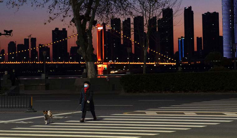 An elderly man crossing the road with a dog by the Yangtze river in Wuhan, Hubei province, the epicentre of China's novel coronavirus disease (COVID-19) outbreak, February 17, 2020 | REUTERS/Stringer/Aly Song 