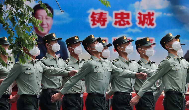 Chinese People's Liberation Army (PLA) soldiers wearing face masks to protect against the spread of the new coronavirus march past a banner depicting Chinese President Xi Jinping at their living squatter inside the Tiananmen Gate in Beijing during a plenary session of China's National People's Congress (NPC) at the Great Hall of the People in Beijing, Monday, May 25, 2020 | AP