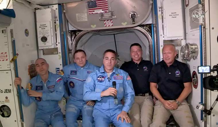 This photo provided by NASA shows Bob Behnken and Doug Hurley, far right, joining the crew at the International Space Station, after the SpaceX Dragon capsule pulled up to the station and docked Sunday, May 31, 2020 | NASA via AP
