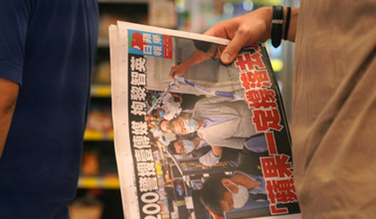 A man waits to pay for a 'Apple Daily' newspaper with the headline 'Apple Daily will fight on' after media mogul and founder of 'Apple Daily' Jimmy Lai was arrested | Reuters