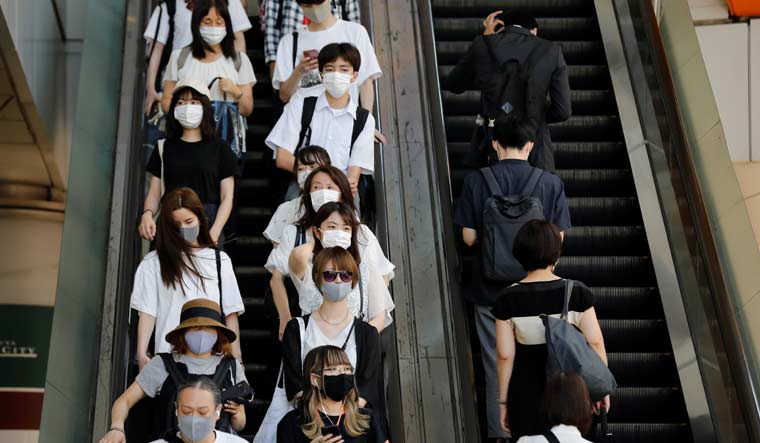 People wearing protective masks ride an escalator amid the coronavirus disease (COVID-19) pandemic in Tokyo, Japan August 3, 2020. REUTERS