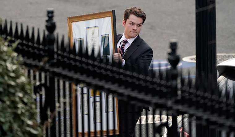 A man carries framed items to a car as he leaves the Eisenhower Executive Office building, inside the White House complex, Thursday, Jan. 14, 2021, in Washington | AP