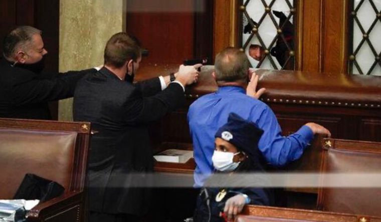 Security personnel with guns drawn maintain a perimeter as protesters attempt to enter the House chamber | AP