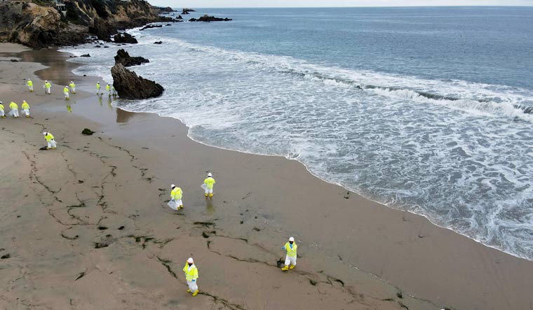 Workers rake up globs of crude oil after more than 3,000 barrels (126,000 gallons) of crude oil leaked from a ruptured pipeline into the Pacific Ocean in Corona Del Mar State Beach, Newport Beach, California, U.S. October 7, 2021 | Reuters