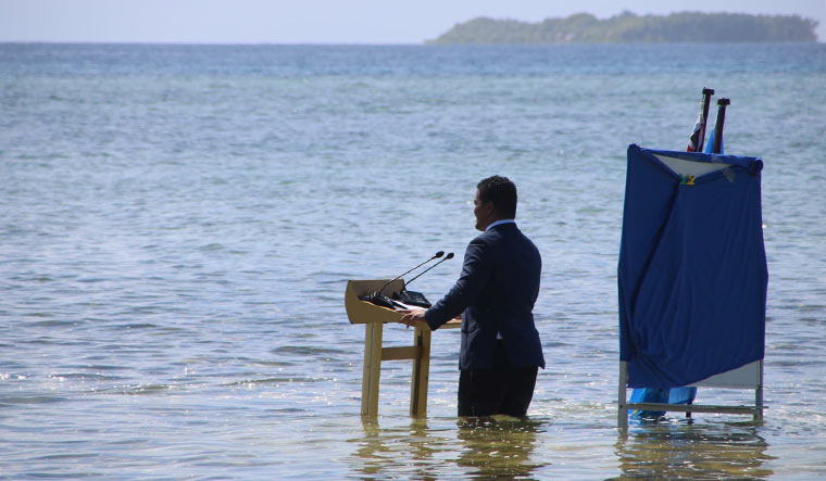 Tuvalu's Minister for Justice, Communication & Foreign Affairs Simon Kofe gives a COP26 statement while standing in the ocean in Funafuti, Tuvalu November 5, 2021 | Courtesy Tuvalu's Ministry of Justice, Communication and Foreign Affairs / Social Media