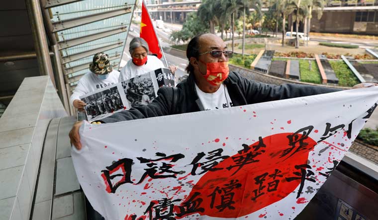 Protesters from a pro-China group carry banners, and Chinese and Japanese national flags during a protest on the anniversary of the Nanjing Massacre, near Japan's consulate in Hong Kong, China, December 13, 2021 | Reuters