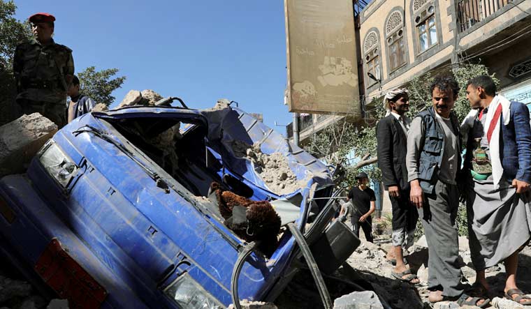 An officer and people stand by a vehicle destroyed by a Saudi-led air strike in Sanaa, Yemen December 24, 2021 | Reuters