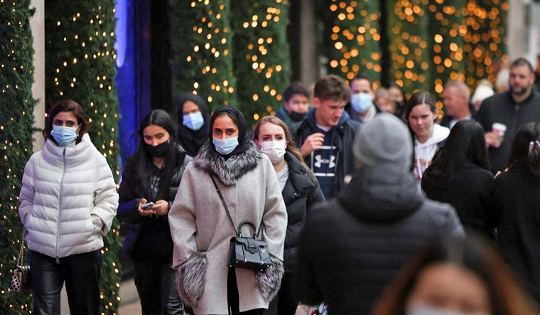 Shoppers wearing face masks to guard against COVID-19 carry bags along Oxford Street in London