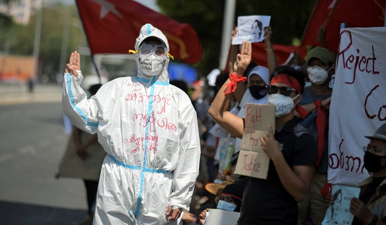 A person wearing personal protective equipment (PPE) flashes a three-fingers salute as he rallies against the military coup and to demand the release of elected leader Aung San Suu Kyi, in Yangon, Myanmar | Reuters