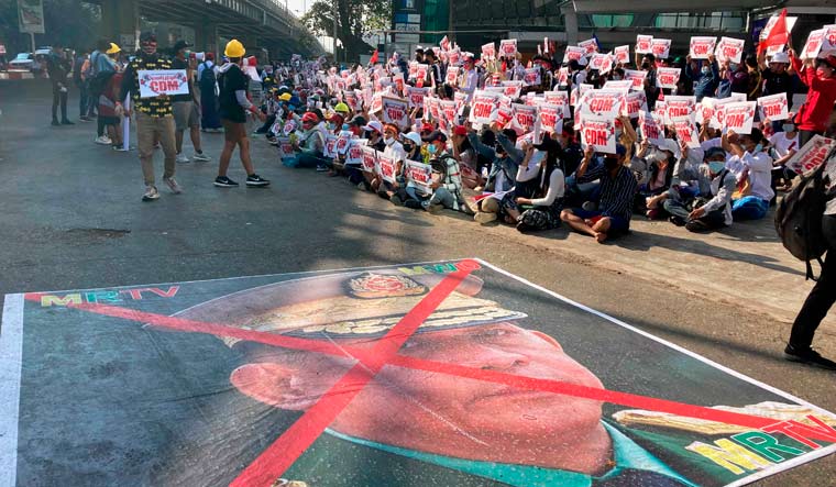 A large image that has an X mark on the face of Commander in chief Senior General Min Aung Hlaing, also Chairman of the State Administrative Council, lies on the road as anti-coup protesters gather outside the Hledan Centre in Yangon | AP