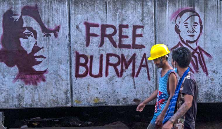 Anti-coup protesters walk past graffiti of deposed Myanmar President Win Myint, right and leader Aung San Suu Kyi in Yangon, Myanmar Wednesday, March 17, 2021 | AP
