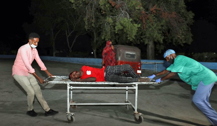 People assist an injured person outside Madina Hospital after a blast Luul Yemeni restaurant near the port in Mogadishu, Somalia | Reuters