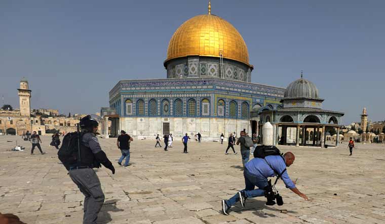 A camera operator falls as an Israeli police officer runs after him during clashes with Palestinians at the compound that houses Al-Aqsa Mosque, known to Muslims as Noble Sanctuary and to Jews as Temple Mount, in Jerusalem's Old City, May 10, 2021 | REUTERS
