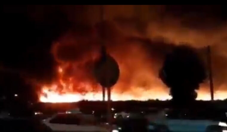 A screenshot from a video showing traffic passing in front of the blaze near the Bushehr Port  