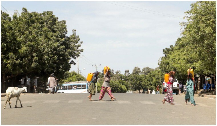 File: Residents carry jerrycans along a street in Dansha town in Tigray Region, Ethiopia | Reuters