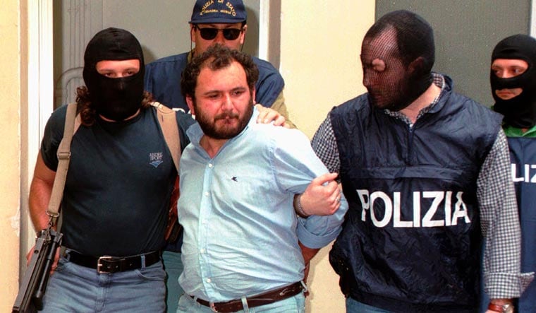 FILE - In this file photo taken on May 21, 1996, Giovanni Brusca is escorted by masked policemen outside Police H.Q. in Palermo, Sicily. Giovanni Brusca, 64, was released from prison this week after serving 25 years of a life term for some of Cosa Nostras most heinous crimes | AP