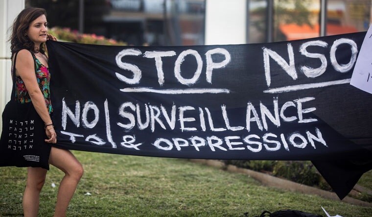 A protester holds a banner during a protest attended by about a dozen people outside the offices of the Israeli cyber firm NSO Group in Herzliya near Tel Aviv | Reuters