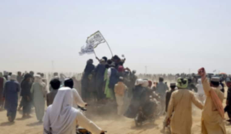 People standing on a vehicle hold Taliban flags as people gather near the Friendship Gate crossing point in the Pakistan-Afghanistan border town of Chaman, Pakistan July 14, 2021 | Reuters