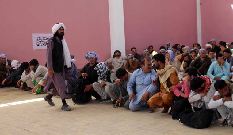 A Taliban fighter stands guard over surrendered Afghan security members forces in the city of Ghazni, southwest of Kabul, Afghanistan, Friday, Aug. 13, 2021 | AP 
