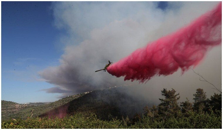 A firefighting plane disperses fire retardant as it assists in extinguishing a fire near the Israeli village of Shoresh at the outskirts of Jerusalem August 15, 2021 | Reuters