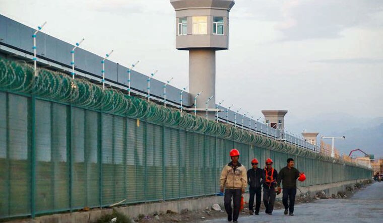 File: Workers walk by the perimeter fence of what is officially known as a vocational skills education centre in Dabancheng in Xinjiang Uighur Autonomous Region, China | Reuters