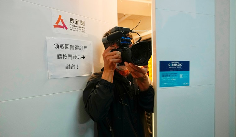 A photographer from 'Citizen News' takes pictures at the entrance of his office | AP