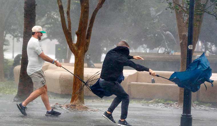 Wind gusts, blowing down King Street, twist umbrellas during Hurricane Ian in Charleston, South Carolina | AP