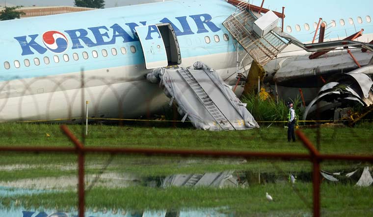 A security guard walks beside a damaged Korean Air plane on Monday Oct. 24, 2022 after it overshot the runway at the Mactan-Cebu International Airport in Cebu, central Philippines | AP