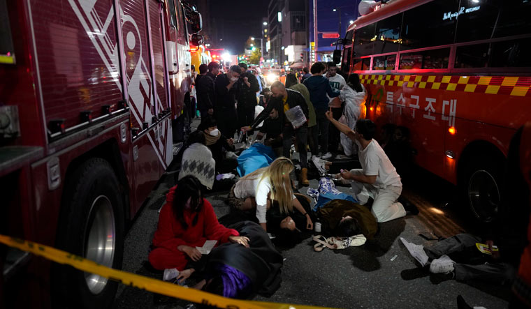 Injured people are helped at the street near the stampede scene in Seoul | AP