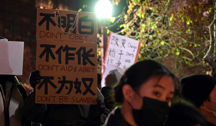 Demonstrators hold up signs during a rally to support protesters in China who have called for the country's leader Xi Jinping to step down amid severe anti-virus restrictions, at Portsmouth Square in San Francisco | AP