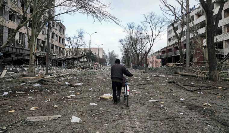 A man walks with a bicycle in a street damaged by shelling in Mariupol, Ukraine, Thursday, March 10, 2022 | AP
