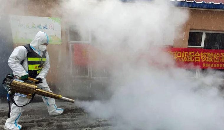 A volunteer disinfects the area as it snows during the Covid-19 lockdown in Changchun in northeast China's Jilin province | AP